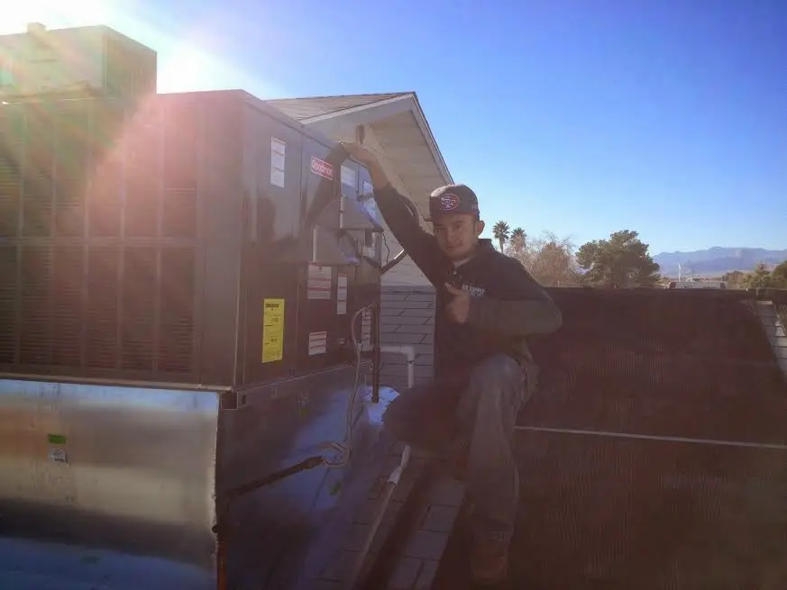HVAC technician performing Air Duct Cleaning on a rooftop unit in Dulles Town Center